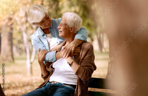 Love, senior couple and hug in park on bench, bonding and romantic together outdoor. Romance, mature man and elderly woman embrace, loving or happy for relationship, marriage and retirement in nature © Anela/peopleimages.com