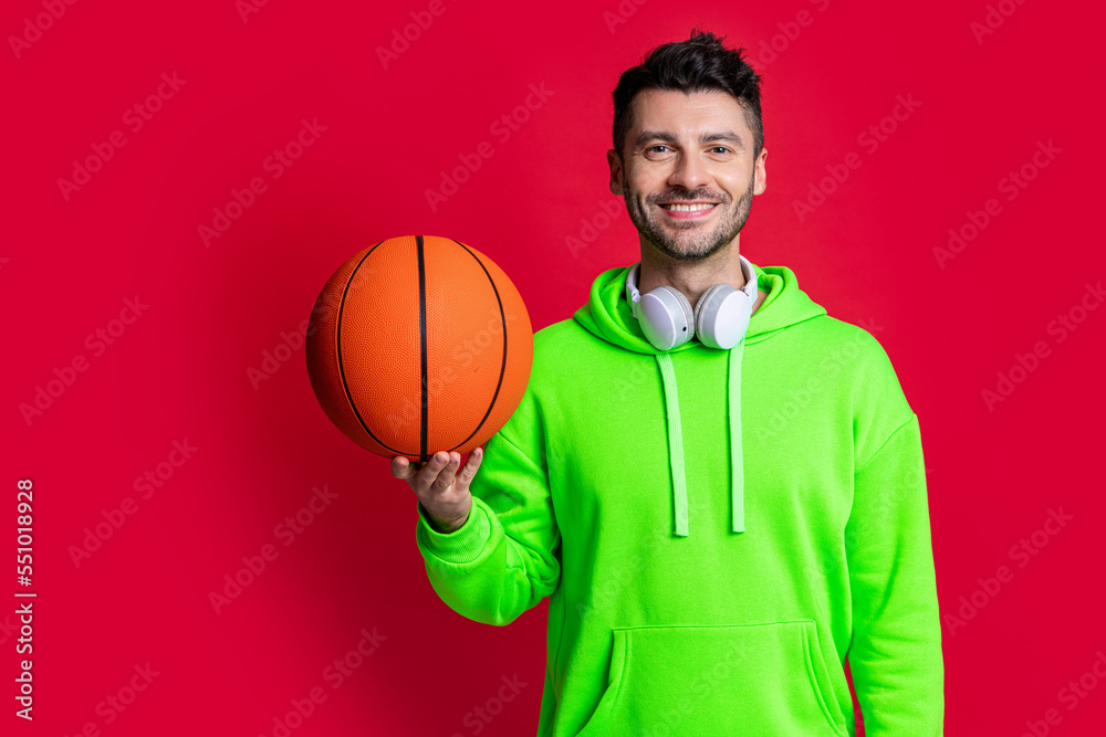 Happy man holding basketball ball. Basketball player smiling isolated on red. Basketball sport