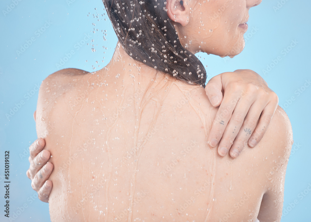 Back, woman and shower for skincare, clean and hygiene against blue studio background. Young female, girl and liquid drops for washing, body care or natural beauty for wellness, water splash or relax Back, woman and shower for skincare, clean and hygiene against blue studio background. Young female, girl and liquid drops for washing, body care or natural beauty for wellness, water splash or relax