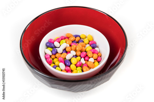 Fennel seed candy in a white red and black bowl isolated over white