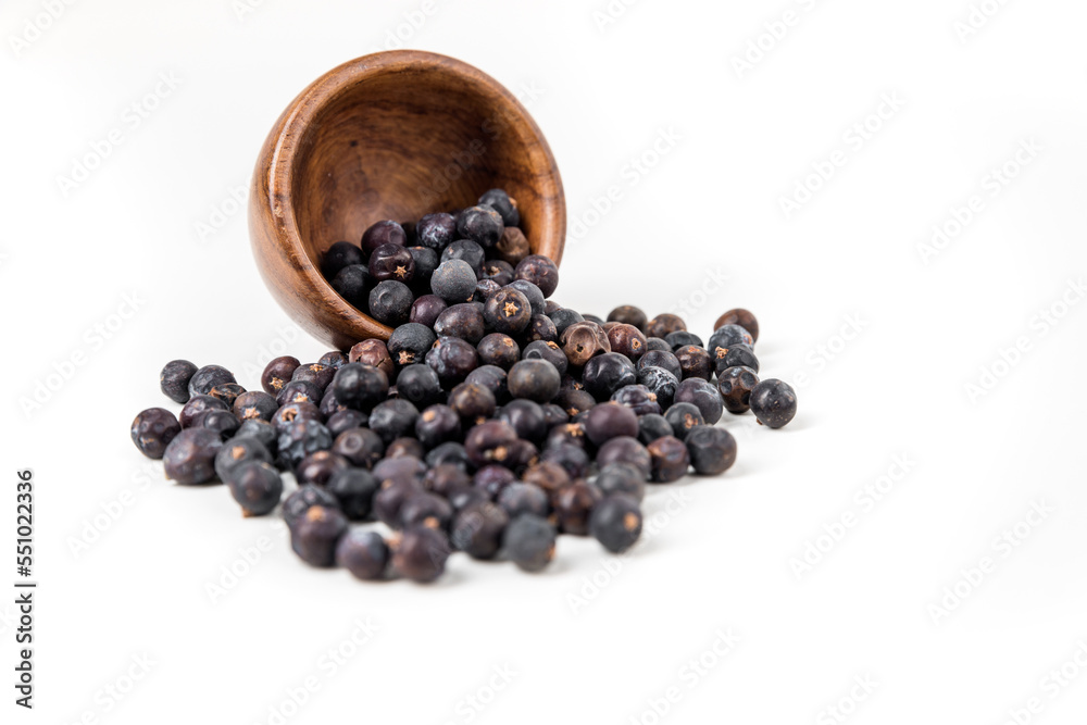Juniper berries spilling from a wood bowl isolated over white focus on bowl Juniper berries spilling from a wood bowl isolated over white focus on bowl
