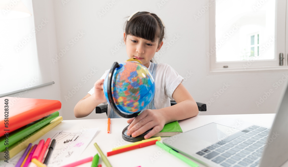 Asia kid girl funny with use magnifying glass to earth model in living room at home Asia kid girl funny with use magnifying glass to earth model in living room at home