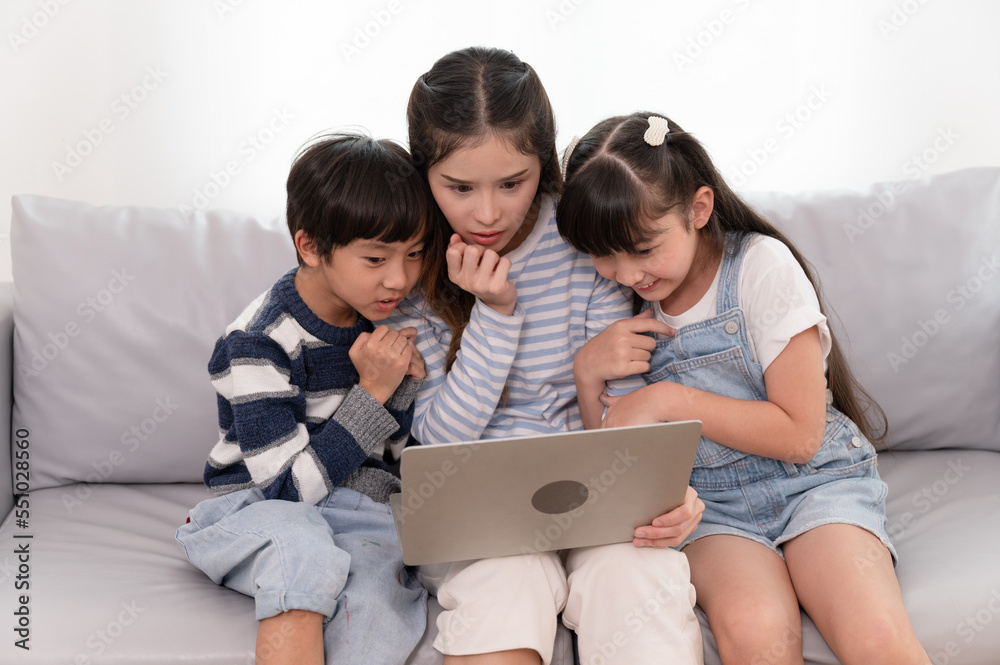 Asia mother and son with daughter fear of see horror movie in notebook computer at home Asia mother and son with daughter fear of see horror movie in notebook computer at home