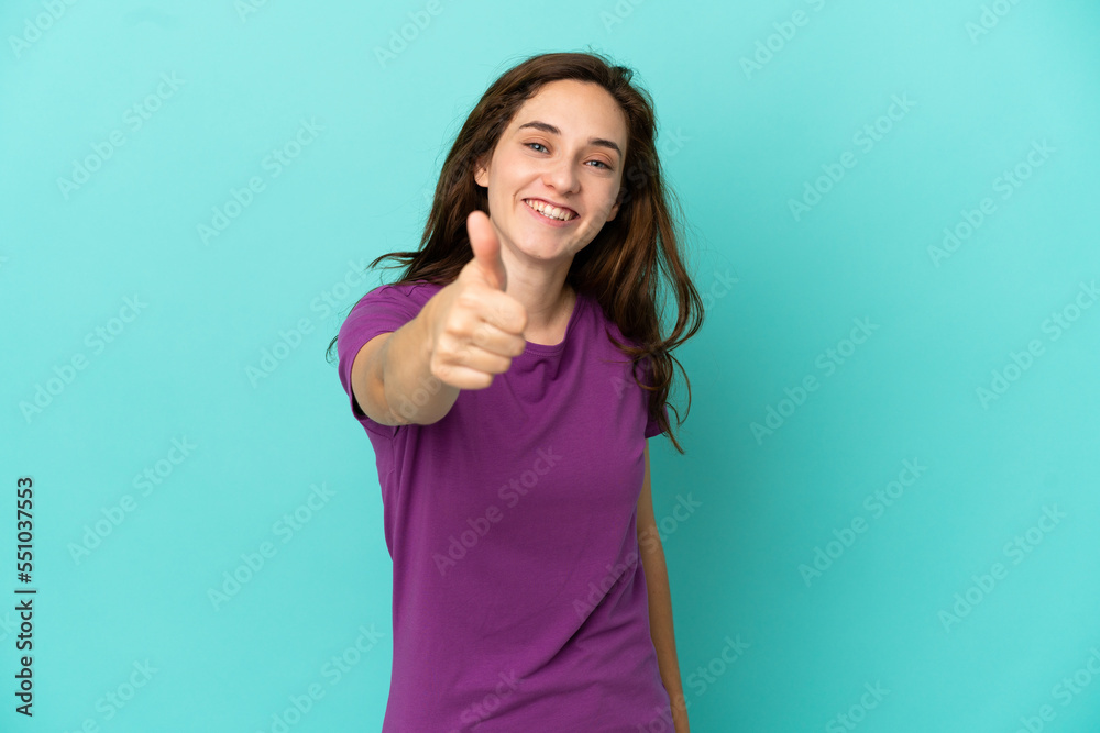 Young caucasian woman isolated on blue background with thumbs up because something good has happened Young caucasian woman isolated on blue background with thumbs up because something good has happened