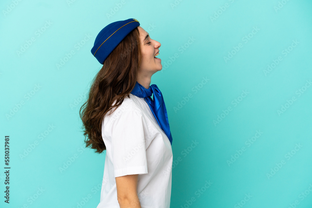 Airplane stewardess woman isolated on blue background laughing in lateral position Airplane stewardess woman isolated on blue background laughing in lateral position
