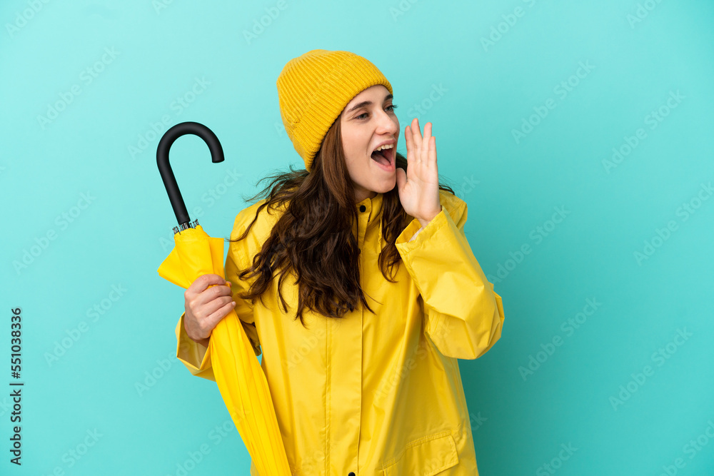 Young caucasian man holding an umbrella isolated on blue background shouting with mouth wide open to the side