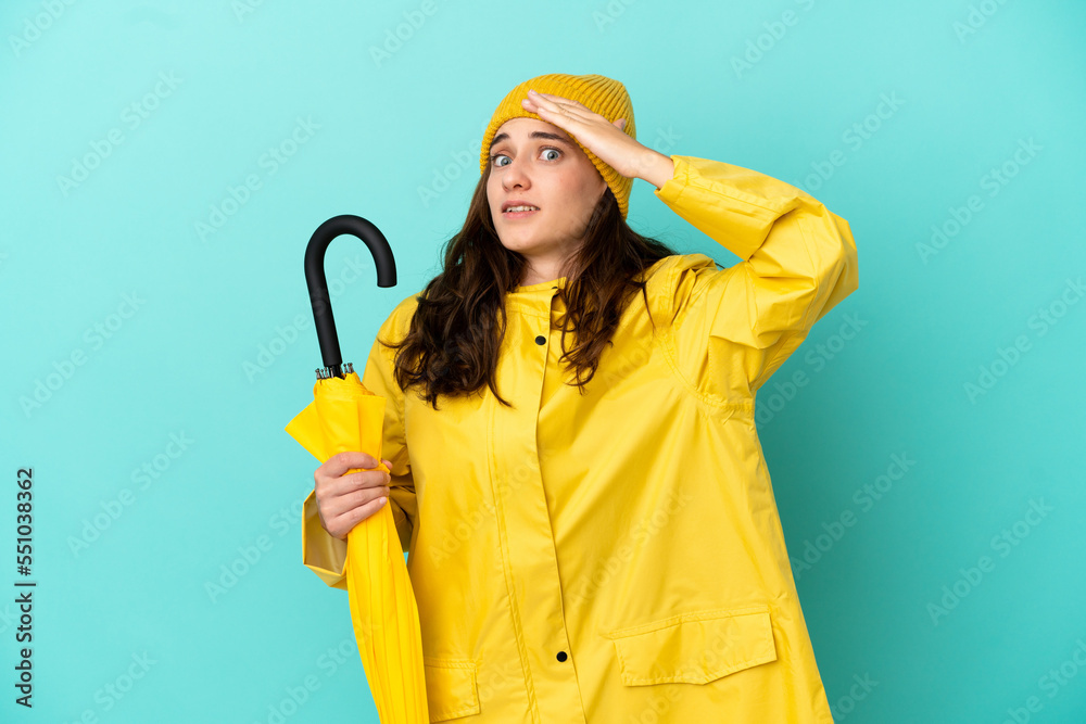 Young caucasian man holding an umbrella isolated on blue background doing surprise gesture while looking to the side Young caucasian man holding an umbrella isolated on blue background doing surprise gesture while looking to the side