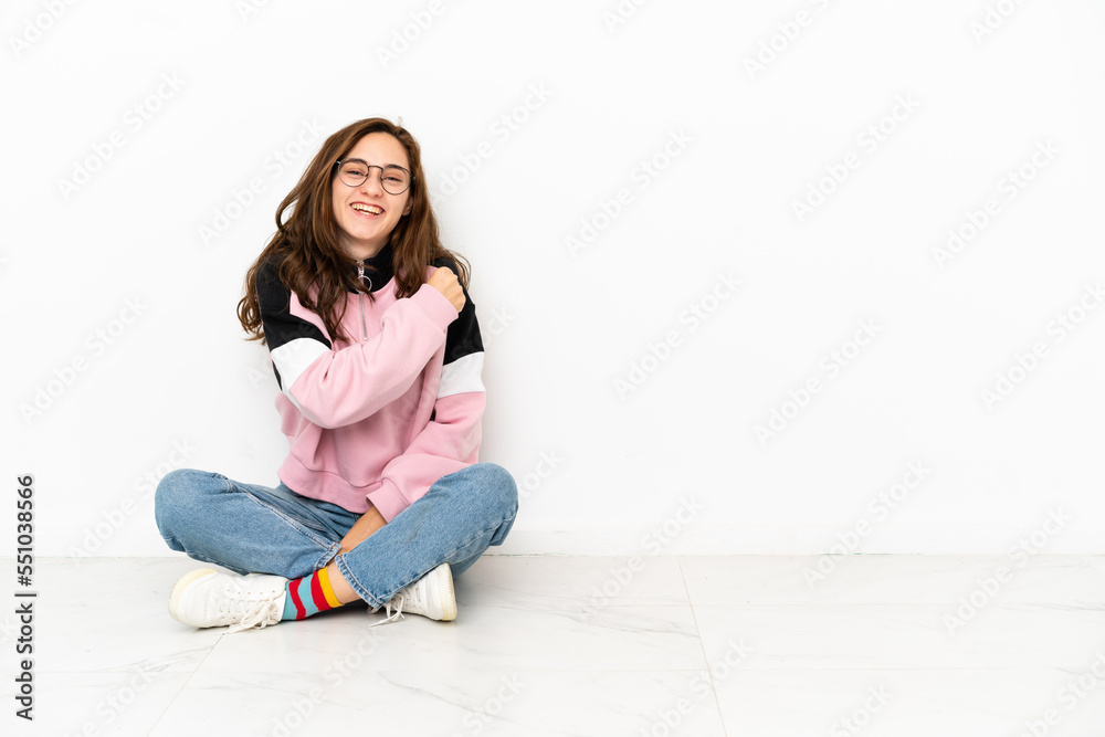 Young caucasian woman sitting on the floor isolated on white background celebrating a victory