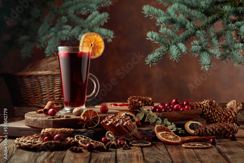 Hot Christmas drink with spices and fruits on an old wooden table.