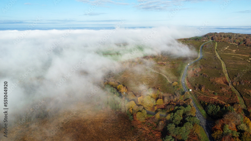 Mist rolling in across a moorland road. A winding road cuts across a wintery Moor with a large Bank of foggy mist sweeps in from the left of the picture. Mist rolling in across a moorland road. A winding road cuts across a wintery Moor with a large Bank of foggy mist sweeps in from the left of the picture.