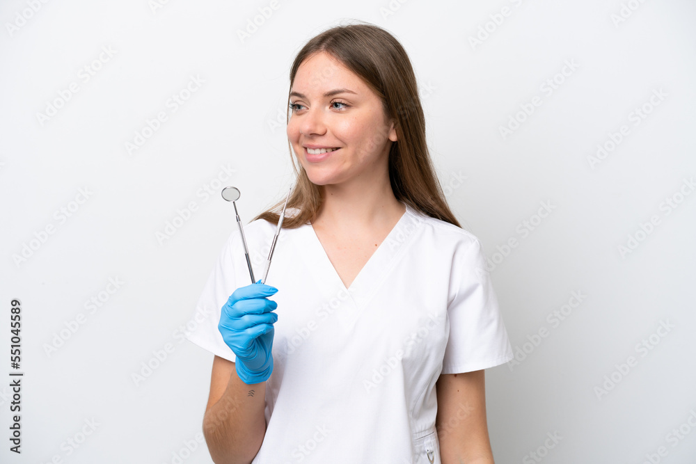 Dentist woman holding tools isolated on white background looking to the side and smiling Dentist woman holding tools isolated on white background looking to the side and smiling
