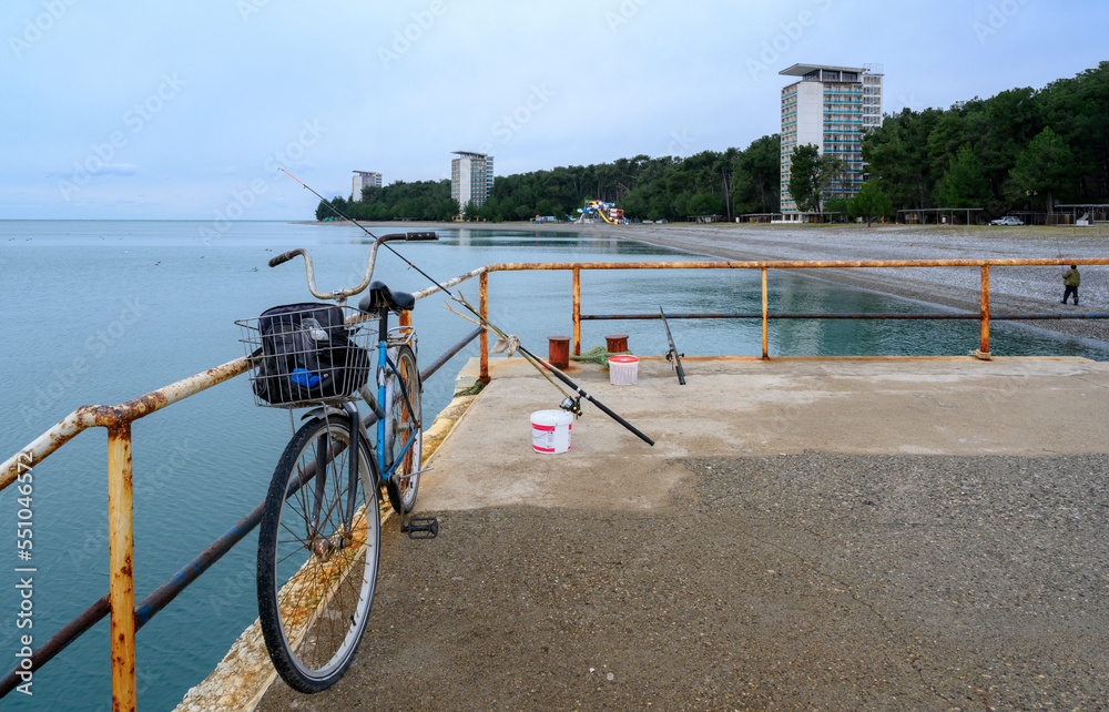 Cape Pitsunda embankment with an old bicycle and a fisherman's fishing rod on the seashore in Abkhazia in winter Cape Pitsunda embankment with an old bicycle and a fisherman's fishing rod on the seashore in Abkhazia in winter
