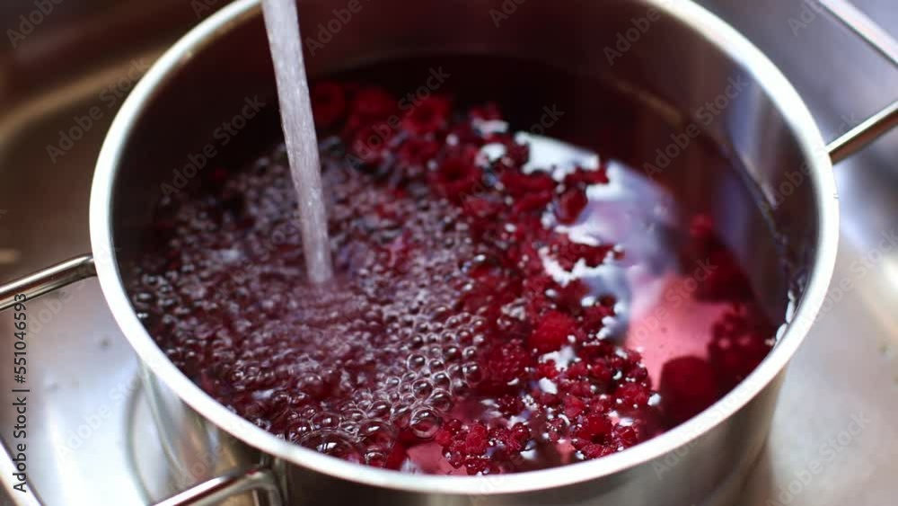 Water flows into a pot with raspberries for making compote. 4K. Water flows into a pot with raspberries for making compote. 4K.