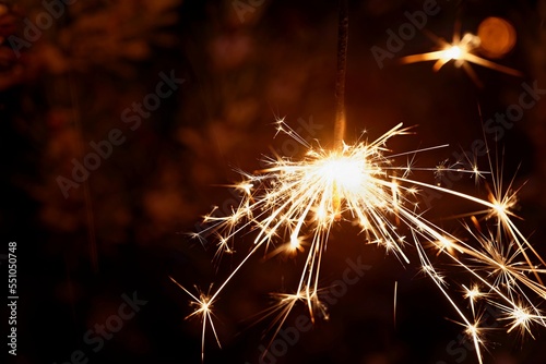 Christmas background. A sparkler on a Christmas tree in the evening outside with snow. Concept for winter season  holidays and new year 2023.
