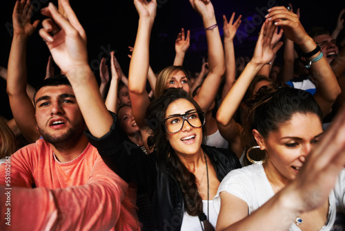 Crowd, concert and people in stadium for music, rock or event with community, energy or hands in air. Group, fans and party for music festival, dance or friends together in arena in night in New York