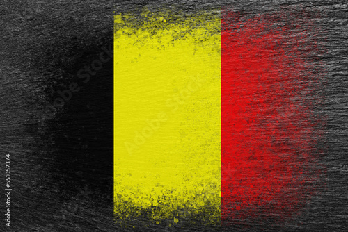 Flag of Belgium. Flag is painted on black slate stone. Stone background. Copy space. Textured background