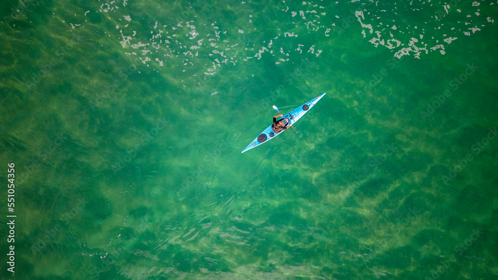 Top view of a man paddles a kayak in raging sea water Top view of a man paddles a kayak in raging sea water