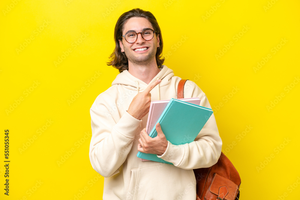 Young student handsome man isolated on yellow background pointing to the side to present a product Young student handsome man isolated on yellow background pointing to the side to present a product