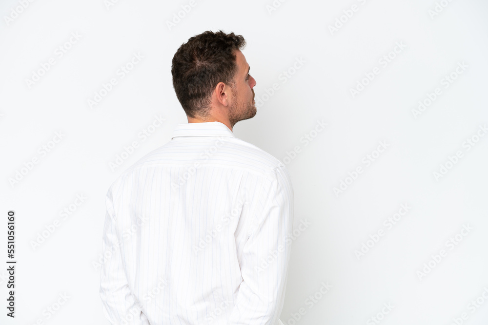 Young caucasian handsome man isolated on white background in back position and looking back