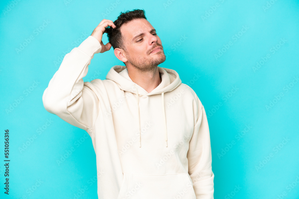 Young caucasian handsome man isolated on blue background having doubts while scratching head Young caucasian handsome man isolated on blue background having doubts while scratching head