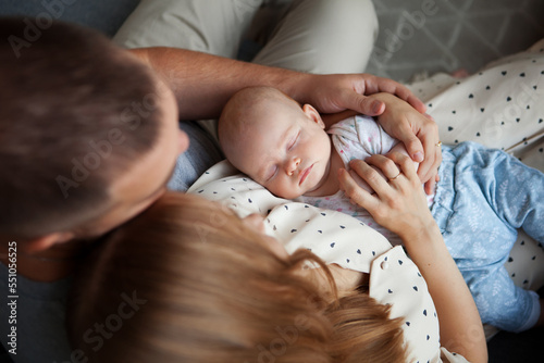 Photos Portrait of sleeping newborn baby in arms of parents, mom and dad, top view