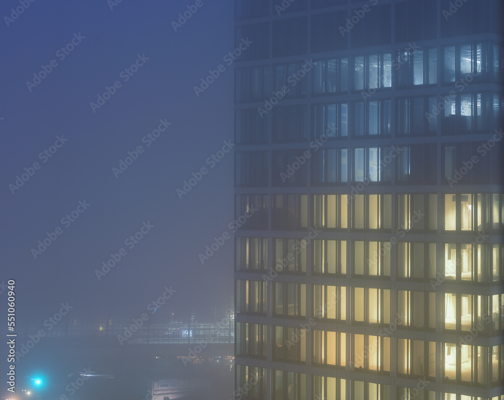 Fototapeta premium illuminated office tower on a foggy night.