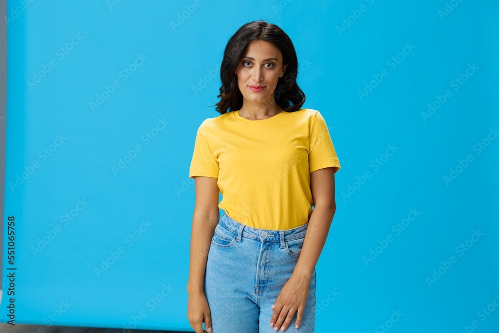 Woman in yellow t-shirt on blue background posing gestures emotions and signals with smile, hands up happiness copy space Woman in yellow t-shirt on blue background posing gestures emotions and signals with smile, hands up happiness copy space