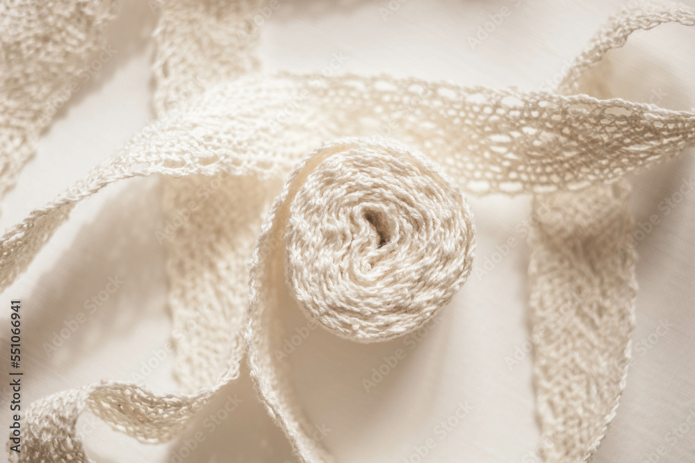 Delicate beige lace on a white table. Top view. Delicate beige lace on a white table. Top view.