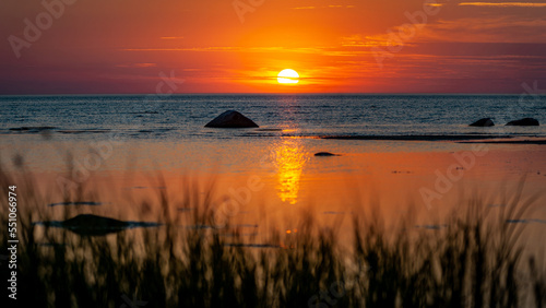 Beautiful view of orange sunset seascape with boulder. Ruhnu  Estonia. Tropical colorful sea landscape. Panorama.