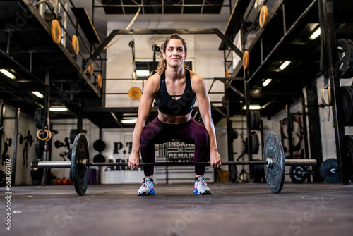 Fototapeta Naklejka Na Ścianę i Meble -  A young female athlete lifts weights in the gym