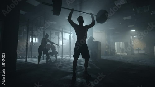 silhouette of weightlifter in gym, brawny man is lifting barbell, deadlift workout in fitness club photo