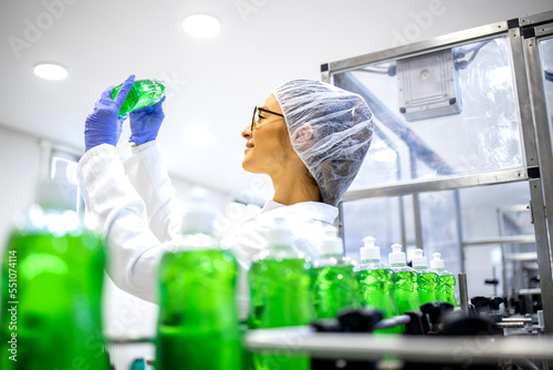 Experienced female factory worker checking quality of cleaning chemicals production.