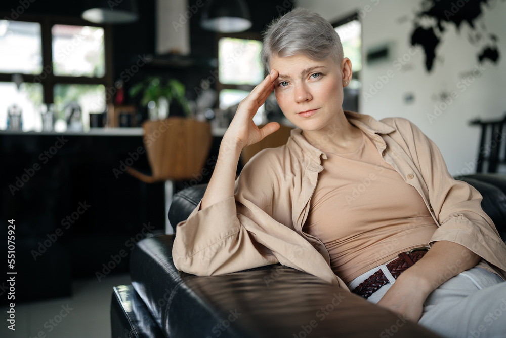 Thinking tired confident and strong woman sitting on the bed in her apartment and looking at the camera. Thinking tired confident and strong woman sitting on the bed in her apartment and looking at the camera.
