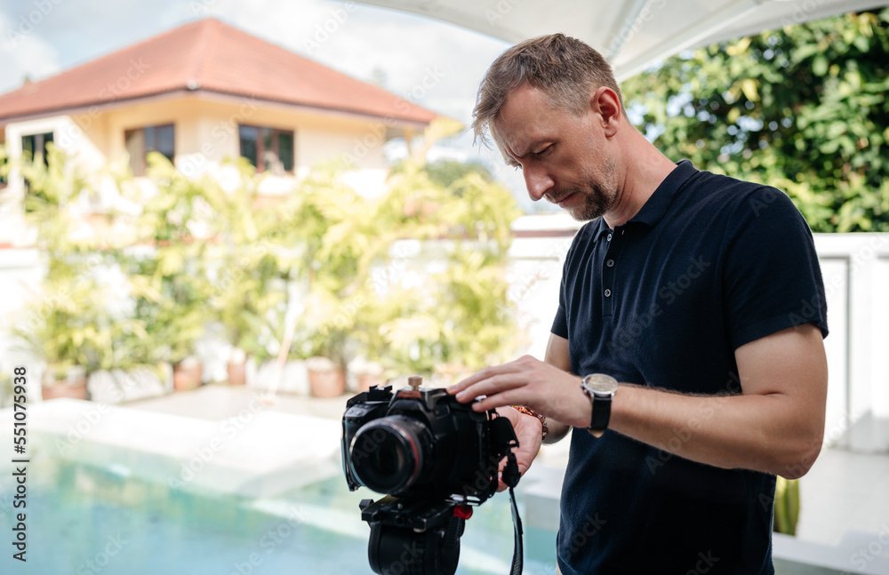 Fascinated man using photo camera outdoors in summer. Fascinated man using photo camera outdoors in summer.