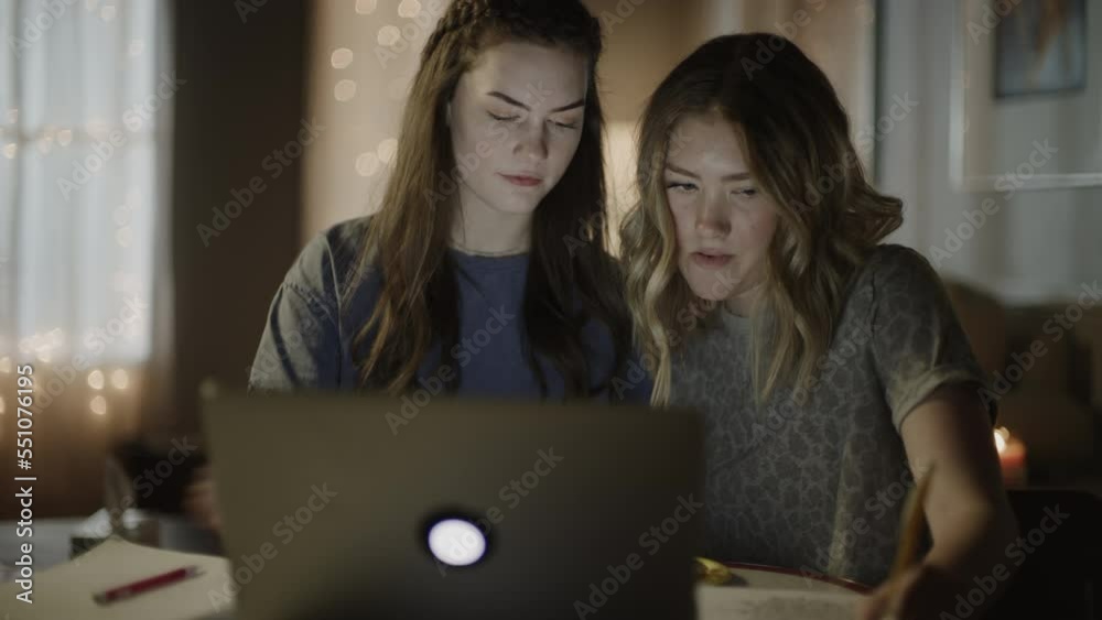 Tilt up to girls studying at online school on laptop and taking notes at night / Cedar Hills, Utah, United States Tilt up to girls studying at online school on laptop and taking notes at night / Cedar Hills, Utah, United States