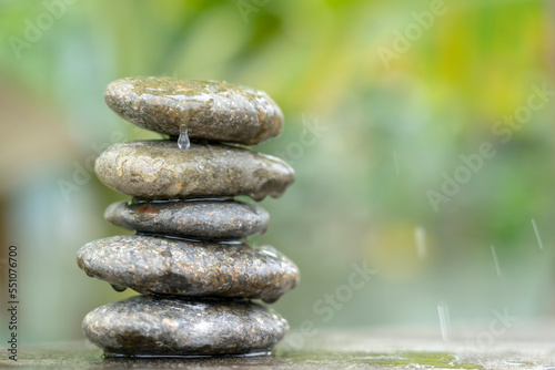 Meditation stones with rain drop water on cement floor on green nature background. Pyramid pebbles free space. Calm, buddhism symbol or aromatherapy set concept.