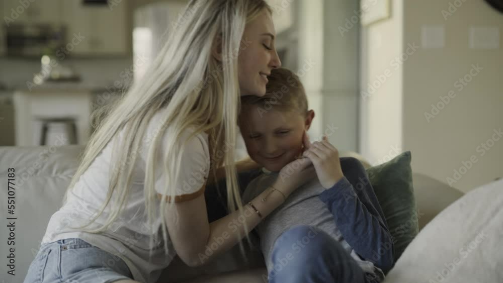 Slow motion of girl on sofa kissing little brother on cheek / Highland, Utah, United States