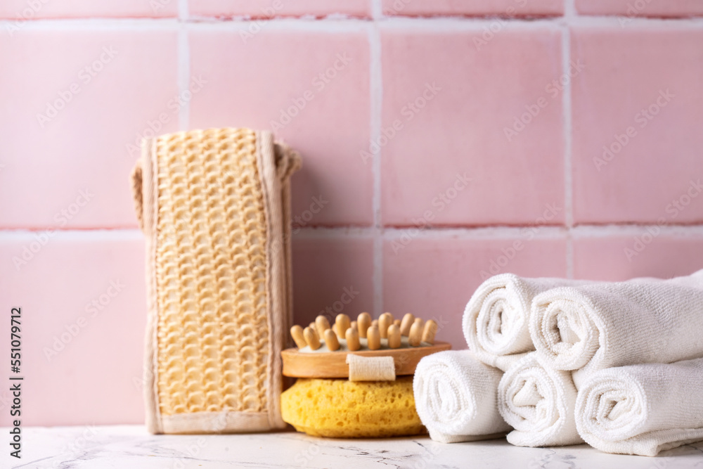 Spa setting with towels, wisk, massager against pink tiled wall. Beauty blogging, salon care concept. Selective focus. Place for text. Spa setting with towels, wisk, massager against pink tiled wall. Beauty blogging, salon care concept. Selective focus. Place for text.