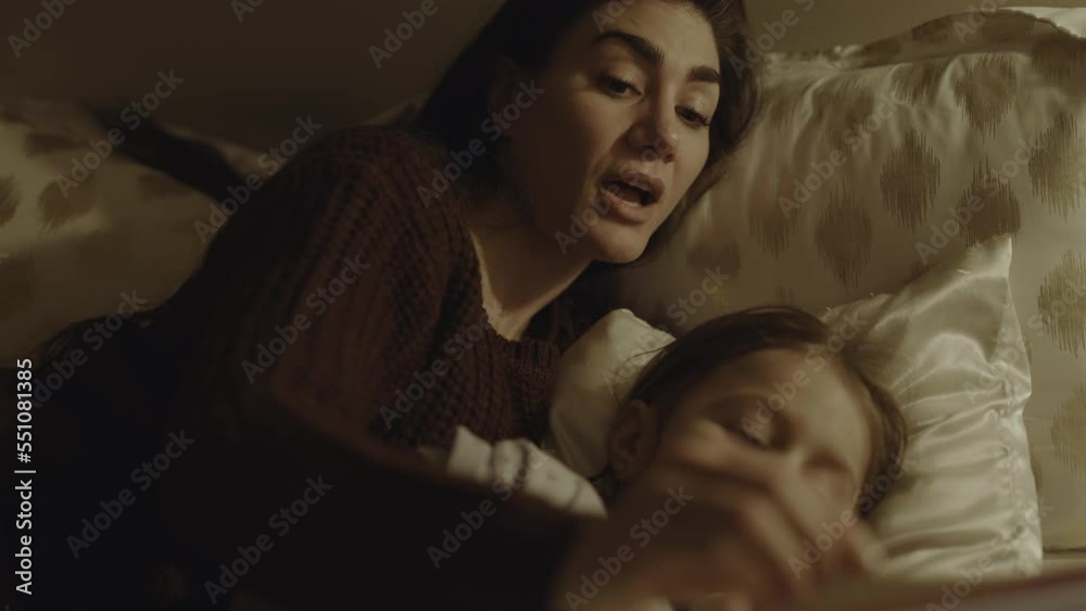 Close up of mother cuddling and reading bedtime story to daughter / South Jordan, Utah, United States Close up of mother cuddling and reading bedtime story to daughter / South Jordan, Utah, United States