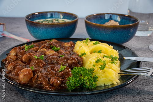 goulash with mushrooms served with masched potatoes, cabbage and spinach in sour cream on blue tableware