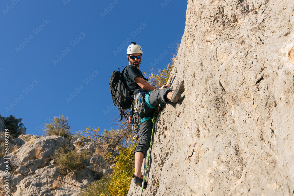 Bearded man climbing cliff in daytime