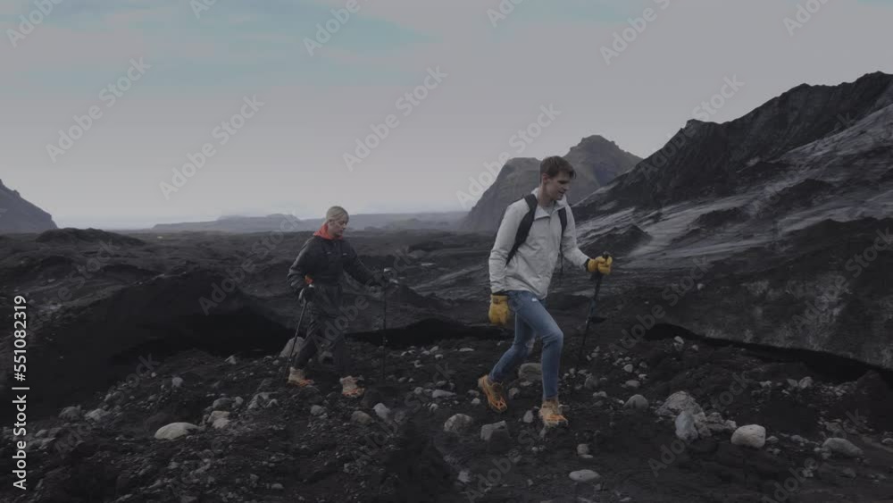 Tracking shot of couple hiking in rocky landscape / Vik, Iceland Tracking shot of couple hiking in rocky landscape / Vik, Iceland