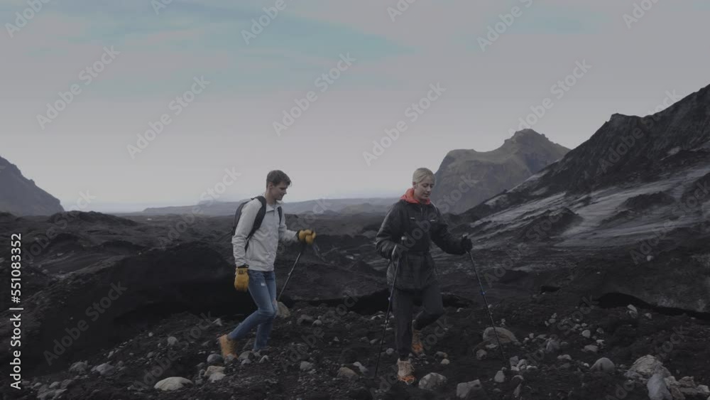 Tracking shot of couple hiking in rocky landscape / Vik, Iceland Tracking shot of couple hiking in rocky landscape / Vik, Iceland