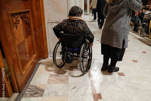Shallow depth of field (selective focus) details with a woman in a wheelchair during a convention.