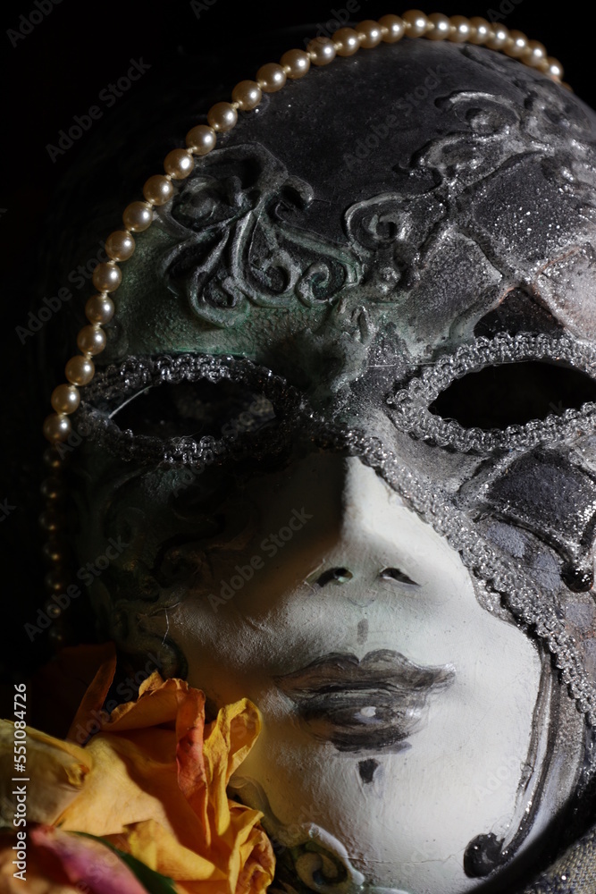 Venetian carnival mask with pearls  and dry rose close up on dark background	
