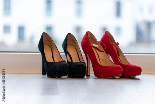 Red and Black high heel pumps in front of a window and on a light floor