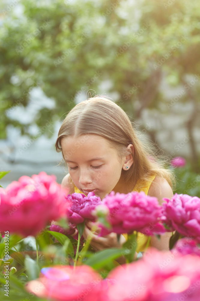 Happy little girl with braces in the garden in bushes of peonies Happy little girl with braces in the garden in bushes of peonies