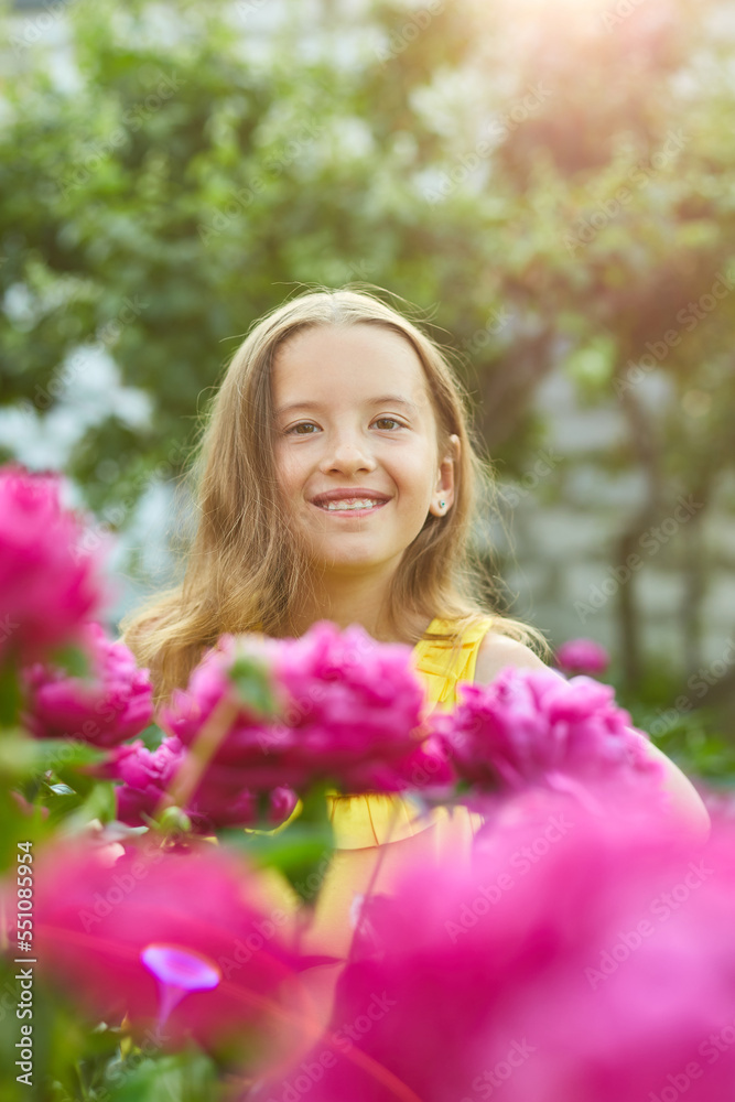 Happy little girl with braces in the garden in bushes of peonies Happy little girl with braces in the garden in bushes of peonies