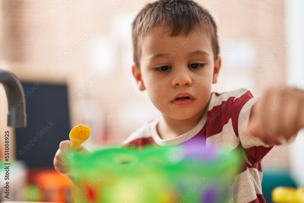 Adorable toddler playing with play kitchen standing at kindergarten Adorable toddler playing with play kitchen standing at kindergarten