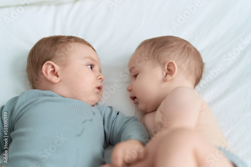 Two toddlers lying on bed at bedroom
